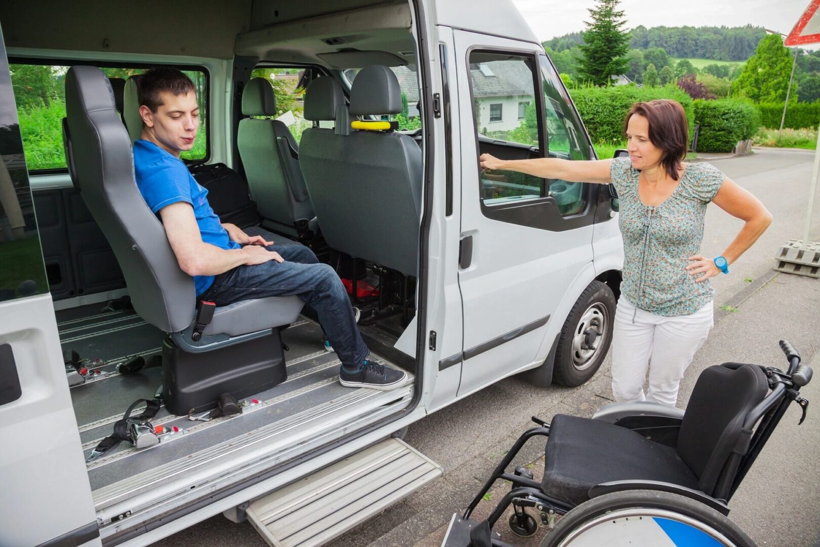 A woman is helping a man in the back of his van.